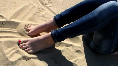 Rot lackierte Zehen im Strandsand